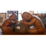 A pair of modern painted carved wood figurines, depicting a boy and girl using pumpkins as pillows