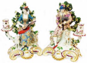 A pair of antique porcelain figural candlesticks, in the Chelsea Derby style decorated with a