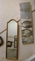 A modern gilt framed narrow oblong wall mirror with bevelled plate and decorative border - sold with