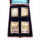 A cased set of four silver napkin rings with engraved decoration and blank cartouches - Birmingham