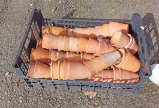 A crate containing a large quantity of old terracotta flowerpots