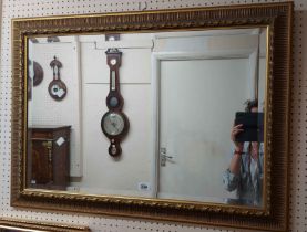 A large modern gilt framed bevelled oblong wall mirror with decorative border