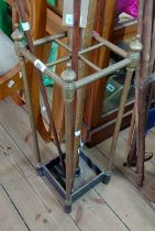 A vintage brass stick stand, set on a cast iron base - drip tray missing