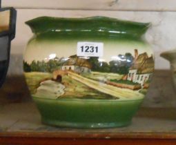 A Watcombe pottery faience small jardiniere with hand painted cottage decoration on a green ground -