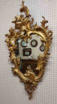 A reproduction Rococo giltwood framed wall mirror with shaped plate