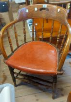 A vintage oak framed bow back elbow chair with spindles and red leather upholstered seat, set on