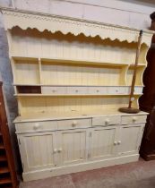 A 1.85m pine two part dresser with cream painted finish, the two shelf open plate rack with six