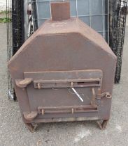 A large old cast iron wood burner enclosed by a panel door