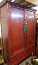 A 1.13m late Chinese red lacquered wood linen cupboard with shelves and drawers enclosed by a pair