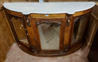 A 1.5m Victorian walnut bow front credenza with shaped marble top and shelves enclosed by three