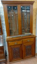 A 1.06m Edwardian mixed wood two part book cabinet with adjustable shelves enclosed by a pair of