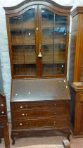 A 93cm early 20th Century walnut two part bureau/bookcase with adjustable shelves enclosed by a pair