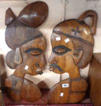 A pair of African carved wood wall plaques depicting the head of a man and woman