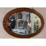 A 70cm early 20th Century copper clad framed bevelled oval wall mirror with embossed and hammered