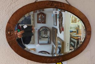 A 70cm early 20th Century copper clad framed bevelled oval wall mirror with embossed and hammered