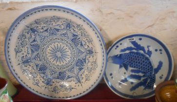 An antique Japanese porcelain dish with blue painted fish decoration (a/f) - sold with a large