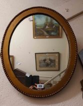An early 20th Century gilt framed oval wall mirror with beaded border