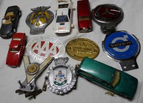 A wooden box containing a quantity of vintage car badges including AA, Mercedes Benz, Volvo owners