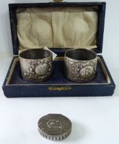 A cased pair of silver napkin rings with embossed decoration 'M' and 'B' initials - dents - sold