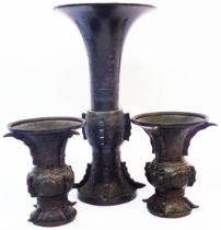 A large antique Chinese bronze altar vase of flared form with cast decoration - sold with two