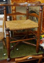An antique stained mixed wood corner elbow chair with woven seagrass seat panel and simple turned