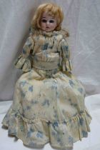 An antique small porcelain headed doll with sleeping eyes, open mouth and sewn leather and stuffed