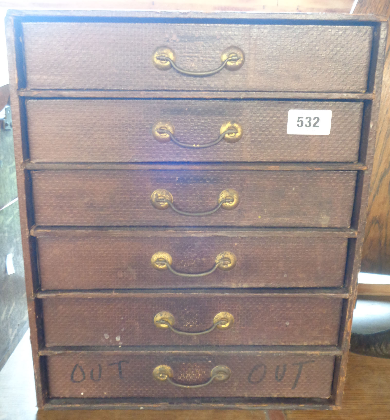 A set of vintage stationery drawers with textured paper finish and brass handles