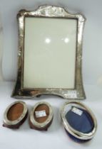 A silver fronted photograph frame with wooden easel back - sold with three small oval similar -