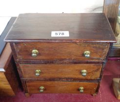 An old miniature wooden chest of drawers, with brass handles - a/f