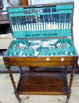 A vintage polished oak table canteen containing a part set of silver plated cutlery, set on a