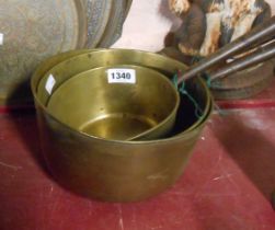 A set of three antique brass graduated saucepans with wrought iron handles