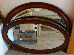 Two early 20th Century stained wood framed bevelled oval wall mirrors