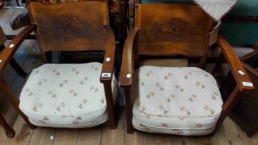 A pair of vintage oak framed low elbow chairs with pressed leather backs depicting a pheasant flying