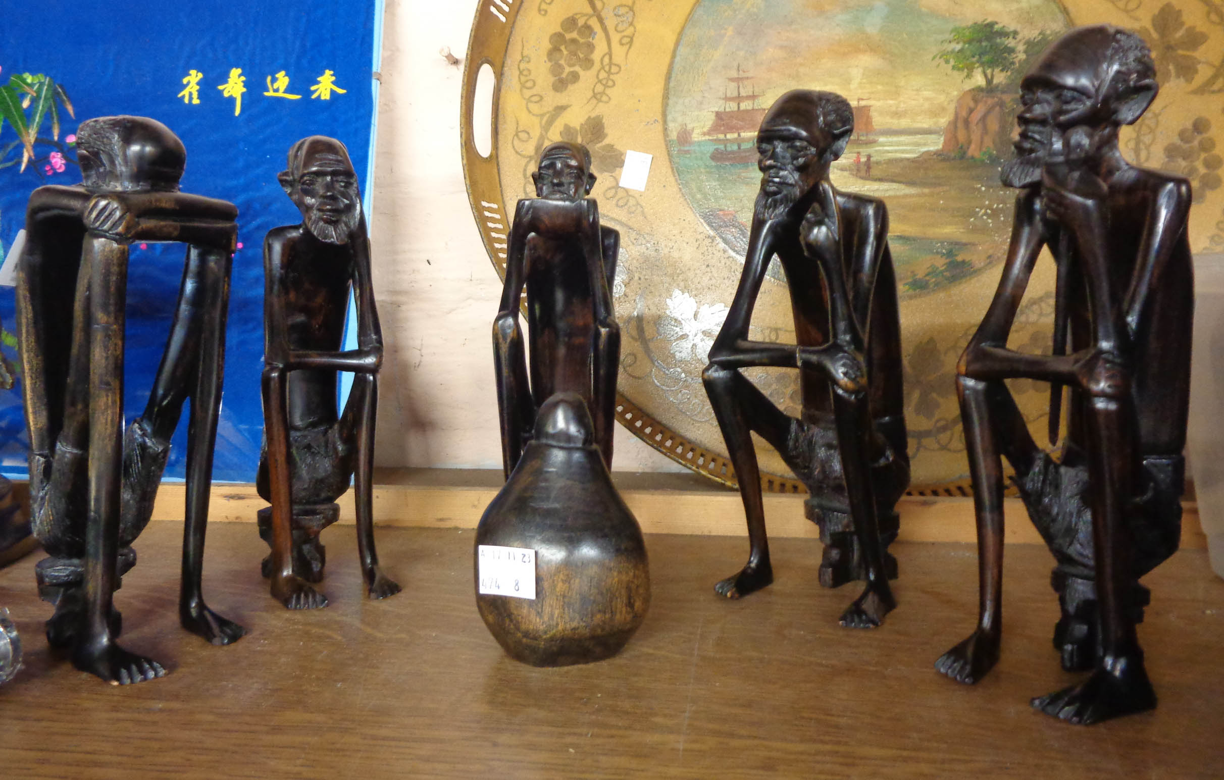 A group of five African carved ebony seated figures with central gourd style pot - some arm cracks