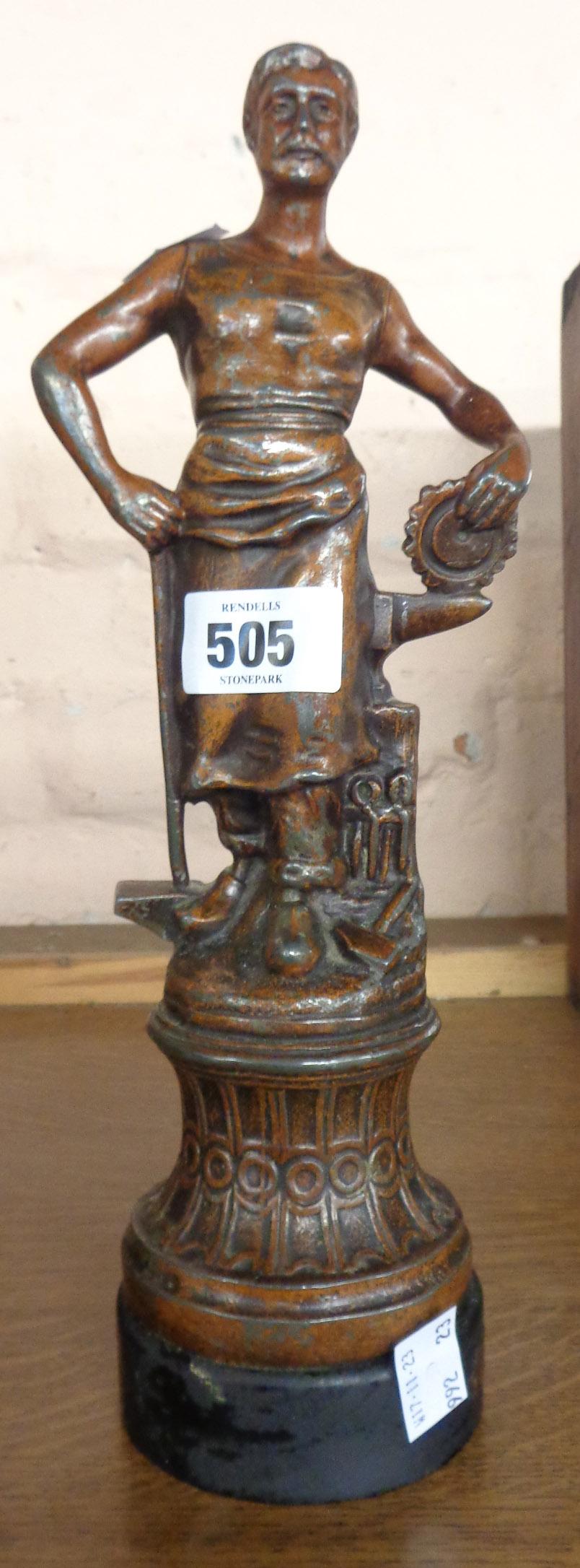 An old spelter figure depicting a blacksmith with bronze effect finish set on wooden plinth