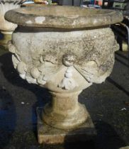 A large concrete pedestal planter with ornate moulded classical decoration