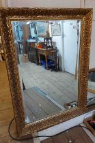 A reproduction gilt framed bevelled oblong wall mirror with decorative border - 76cm X 1.05m