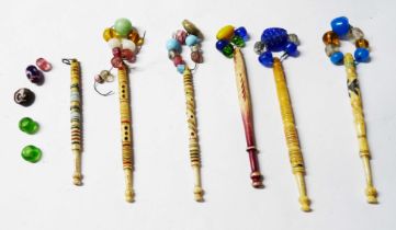 A bag containing six antique carved bone lace bobbins with painted decoration and glass beads