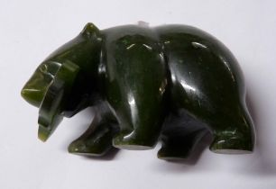 A small Inuit carved hardstone figurine depicting a bear catching a salmon