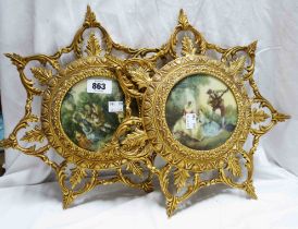 A pair of decorative cast brass frames with gilt finish each containing a panel depicting a