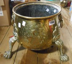 A brass planter with embossed armourial decoration set on lion paw feat with lion mask handles