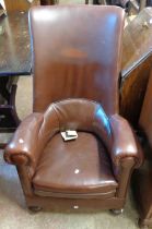 An early 20th Century high back armchair with later studded brown leather upholstery, set on front