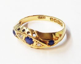 An 18ct. gold ring, set with three cornflower blue sapphires interspersed with tiny diamonds -