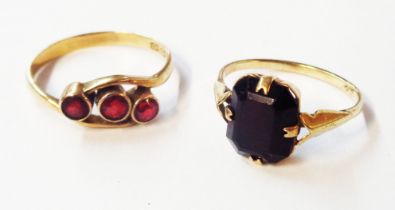 Two marked 9ct. yellow metal rings, one set with oval garnet, the other three small garnets in