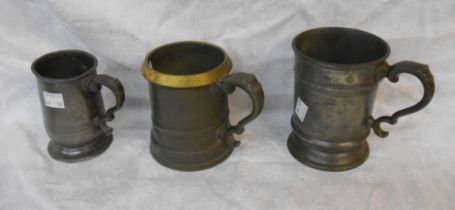 An antique pewter measure with brass rim - sold with two pewter tankards