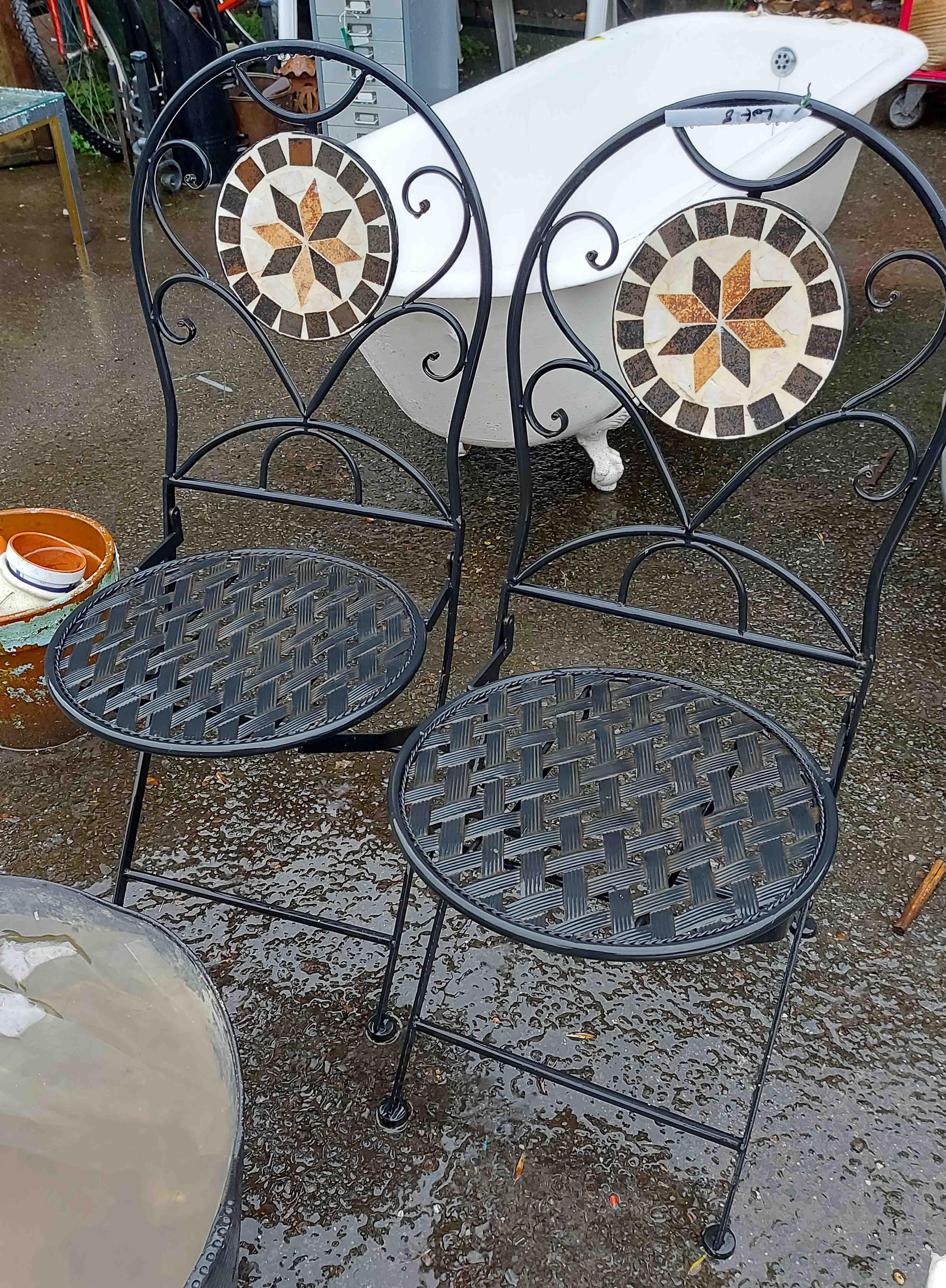 A pair of black metal folding bistro style chairs