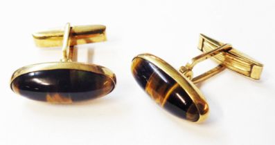 A pair of marked 9ct. yellow metal torpedo shaped panel cufflinks, each set with tiger's eye