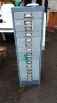 A vintage metal filing chest with flight of fifteen shallow drawers