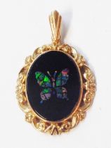 A 375 (9ct.) gold oval pendant with central opal inlaid black onyx panel with butterfly motif within