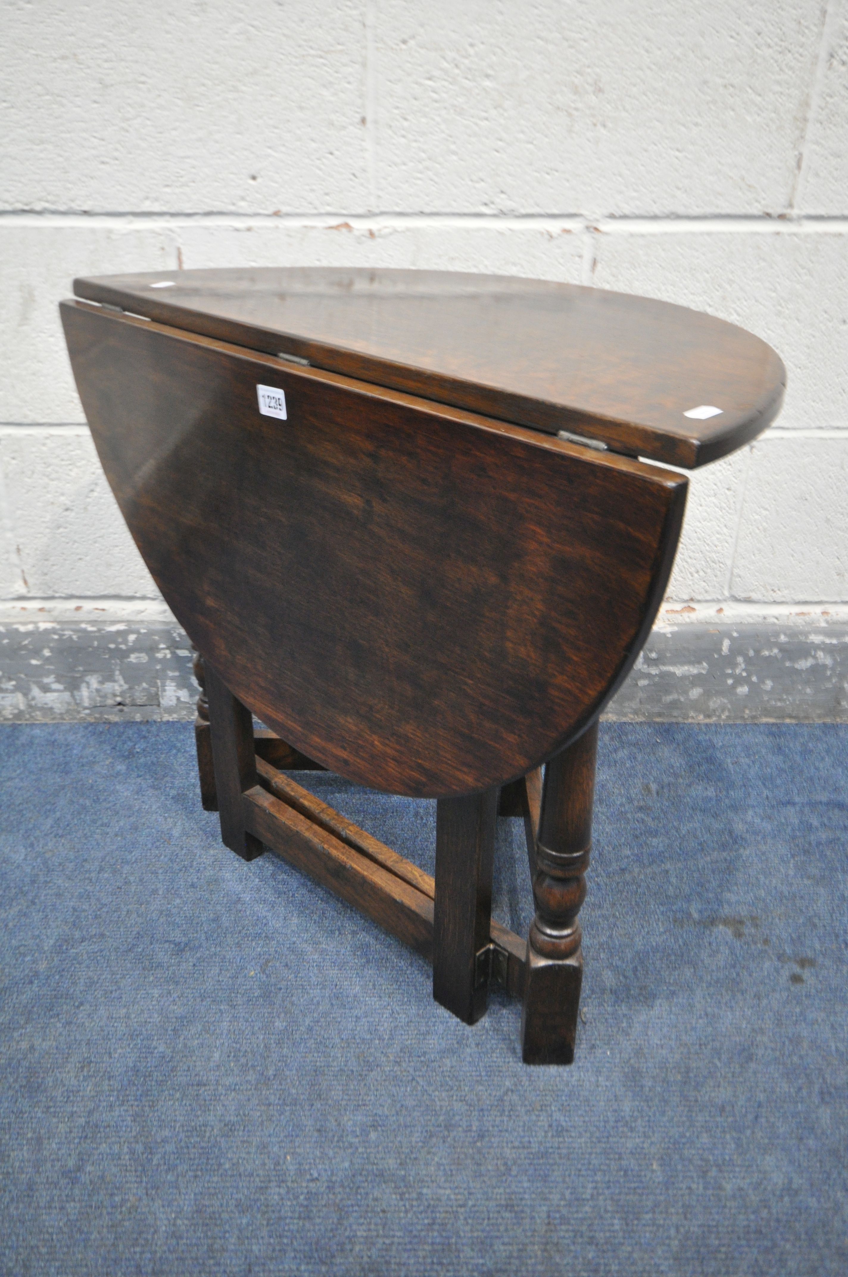 A REPRODUCTION OAK SINGLE DROP LEAF OCCASIONAL TABLE, that opens to a circle, open diameter 69cm x